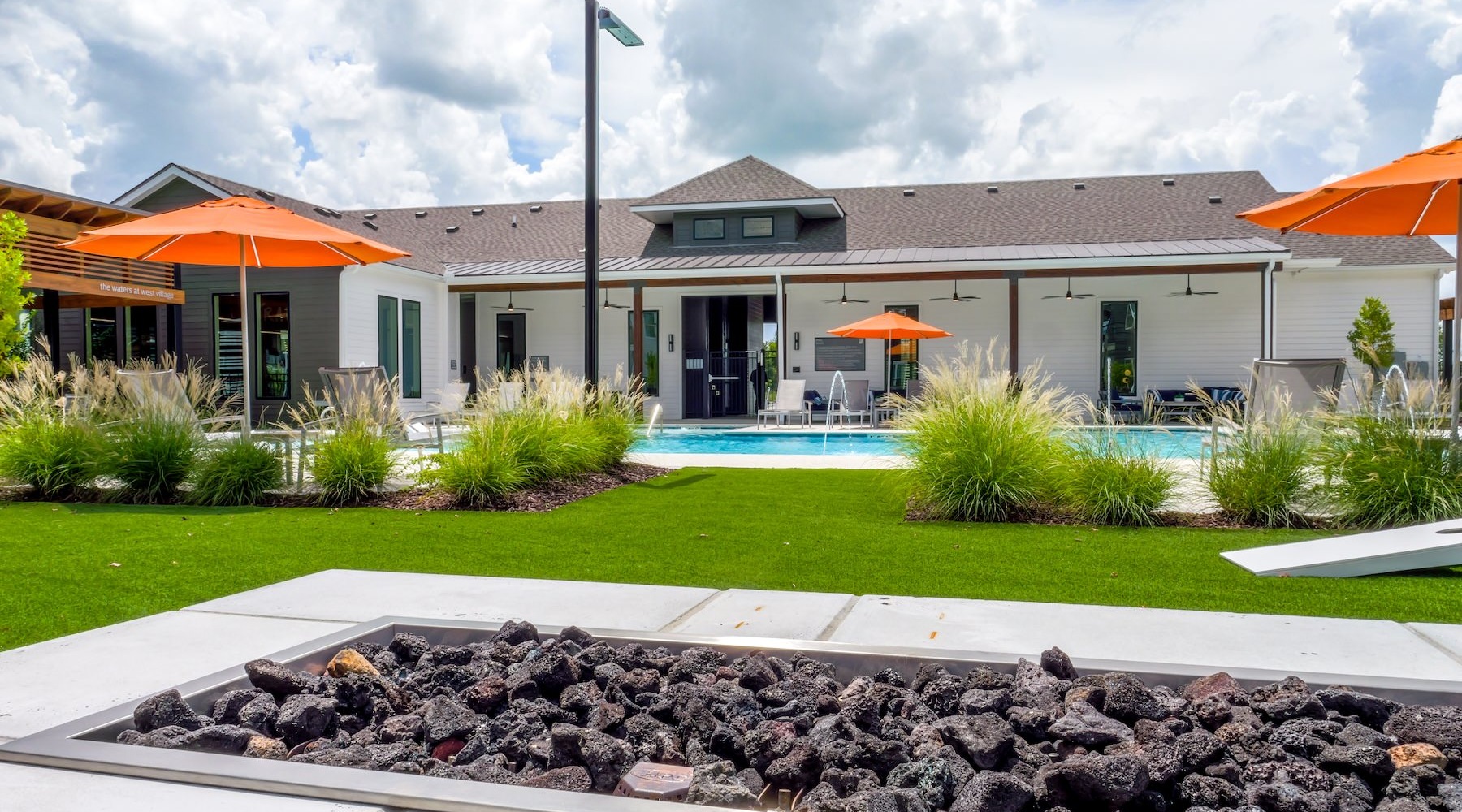 a fire pit with a pool and umbrellas in the background